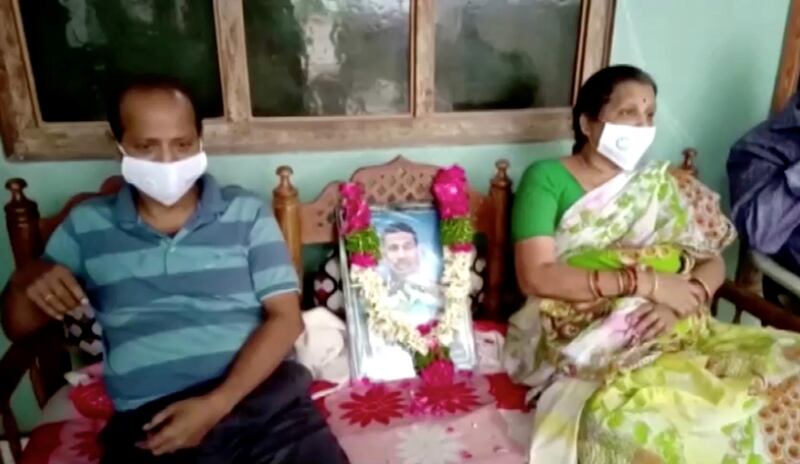 The father and mother of Colonel Santosh Babu, who was killed in border clashes with Chinese troops, sit next to his portrait, in Suryapet,Telangana state, India. REUTERS