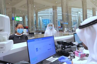 An immigration official checks documents of passenger at Dubai Airport. WAM