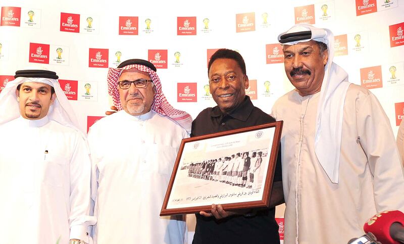 Pele holding a framed picture of a 1973 football match between his former team Santos and UAE club Al Nasr, after receiving it from former players Mohamed Kahoor and Mohammed Al Khous in Dubai, 2014. AFP