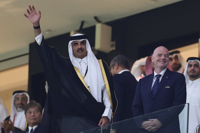 Emir Sheikh Tamim waves to the crowd as he arrives with Fifa president Gianni Infantino. AFP