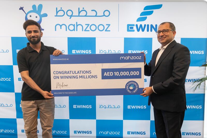 Saad from Pakistan collects his cheque for Dh10 million after winning the Mahzooz weekly draw. Presenting the cheque is Farid Samji from Mahzooz. All photos: Antonie Robertson/The National
