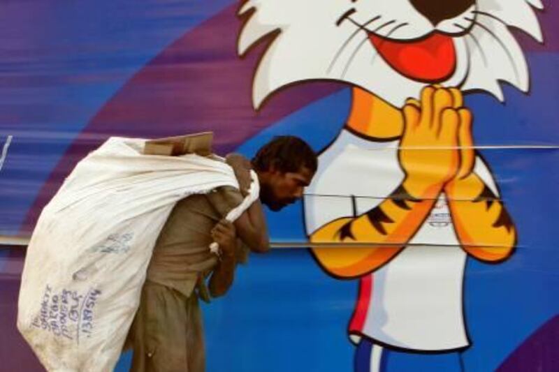 Indian scavenger Shamshul returns a bagful of recyclable trash picked from the roadside, in the backdrop of  Commonwealth Games related banner depicting games mascot Shera, in New Delhi, India, Friday, Sept. 24, 2010. Frantic last-minute preparations for the Commonwealth Games were paying off, international sports officials said Friday, with armies of cleaners making progress at the fetid athletes' village and foreign teams announcing they planned to attend the troubled competition. (AP Photo/Gurinder Osan) *** Local Caption ***  DEL149_India_Commonwealth_Games_Problems.jpg