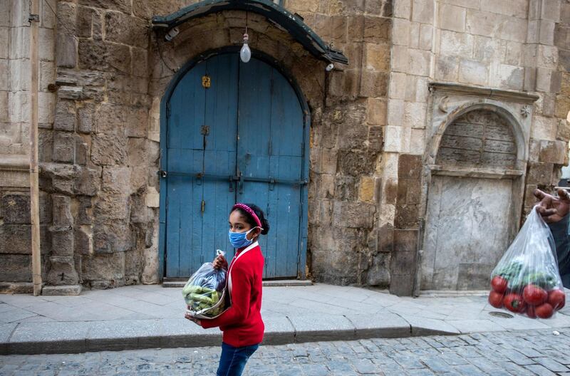 A child wearing face mask walks in front of closed shops shortly before lockdown, in Cairo, Egypt.  EPA