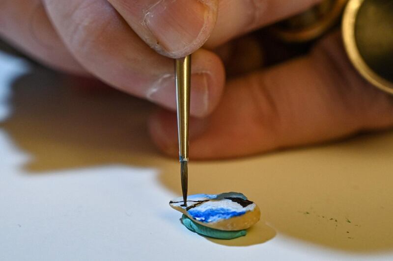 Turkey's micro artist Hasan Kale paints on a broad bean in Istanbul on August 23, 2019.  His canvas could be anything from match sticks, seeds to razors and crown corks. Turkey's micro artist, also known as Turkish Microangelo in reference to Italian Renaissance sculptor and painter Michelangelo, has been hitting his brush onto tiny everyday objects for more than two decades. - RESTRICTED TO EDITORIAL USE - MANDATORY MENTION OF THE ARTIST UPON PUBLICATION - TO ILLUSTRATE THE EVENT AS SPECIFIED IN THE CAPTION
 / AFP / Ozan KOSE / RESTRICTED TO EDITORIAL USE - MANDATORY MENTION OF THE ARTIST UPON PUBLICATION - TO ILLUSTRATE THE EVENT AS SPECIFIED IN THE CAPTION
