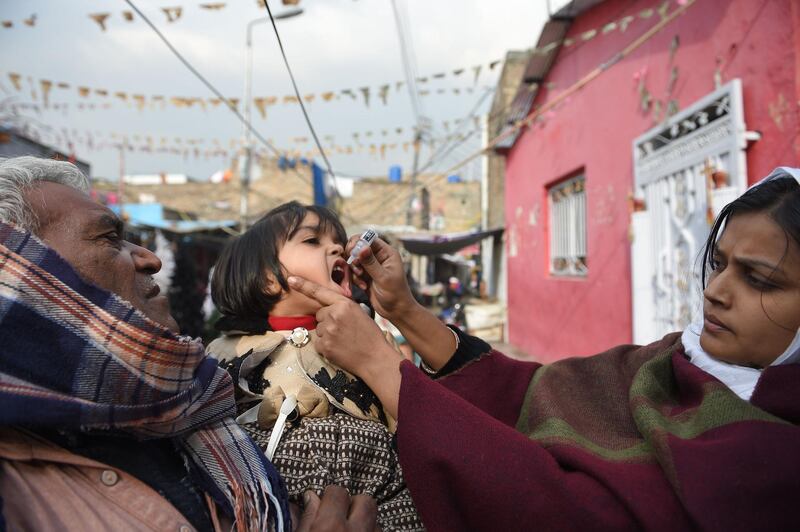 A Pakistani Christian health worker administers polio vaccine drops to a child during a polio vaccination campaign in a Christian colony in Islamabad on December 12, 2018. The United States on Tuesday added Pakistan to its blacklist of countries that violate religious freedom, ramping up pressure over the uneasy ally's treatment of minorities. / AFP / FAROOQ NAEEM
