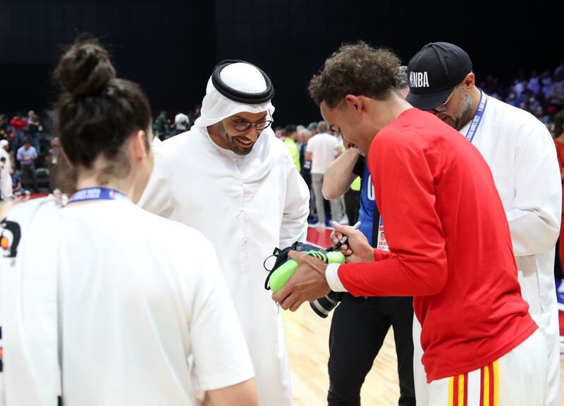 Mohamed Khalifa Al Mubarak, chairman of DCT Abu Dhabi, is given a shoe signed by Atlanta Hawks player Trae Young. Chris Whiteoak / The National