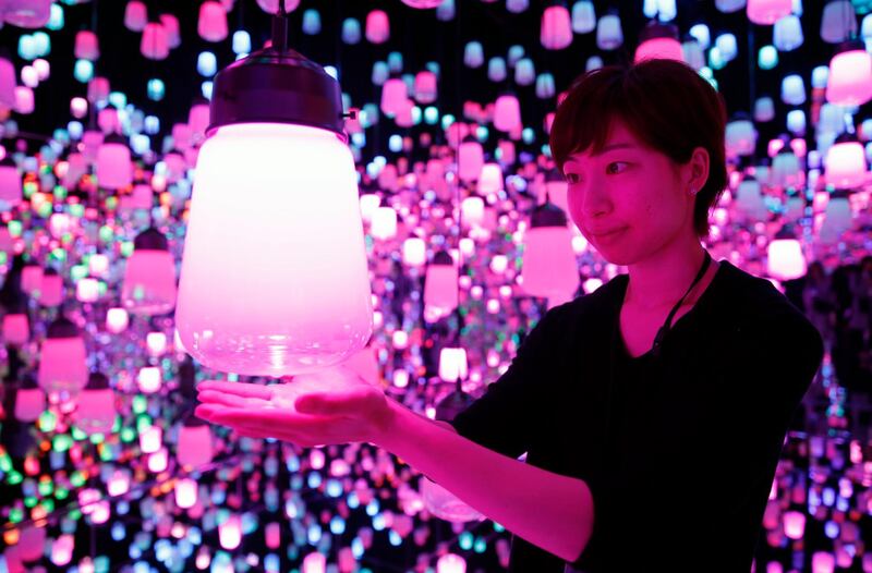 A young woman interacts with a digital artwork in the Forest of Resonating lamps at the digital art museum.