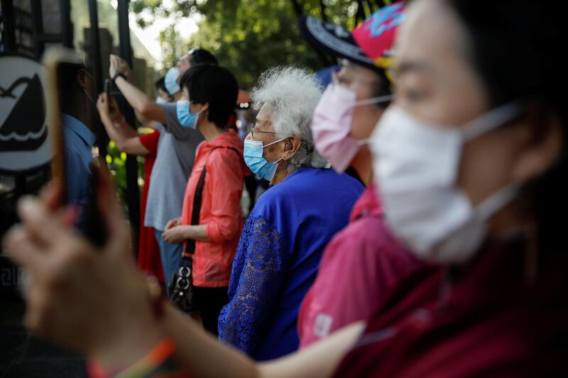 People wearing face masks stand outside a high school as their wards write the annual national college entrance exam, which had been postponed by a month, in Beijing, China. Reuters