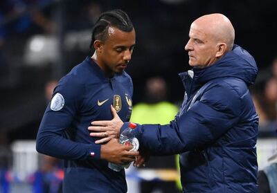 France defender Jules Kounde is consoled by France's assistant coach Guy Stephan after he was injured. AFP