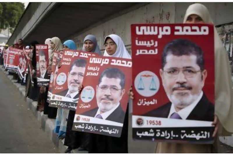 Egyptian women line up to form a human chain as they hold posters of Muslim Brotherhood presidential candidate, Mohammed Morsi with Arabic that reads, "Dr. Mohammed Morsi, president for Egypt, 2012."