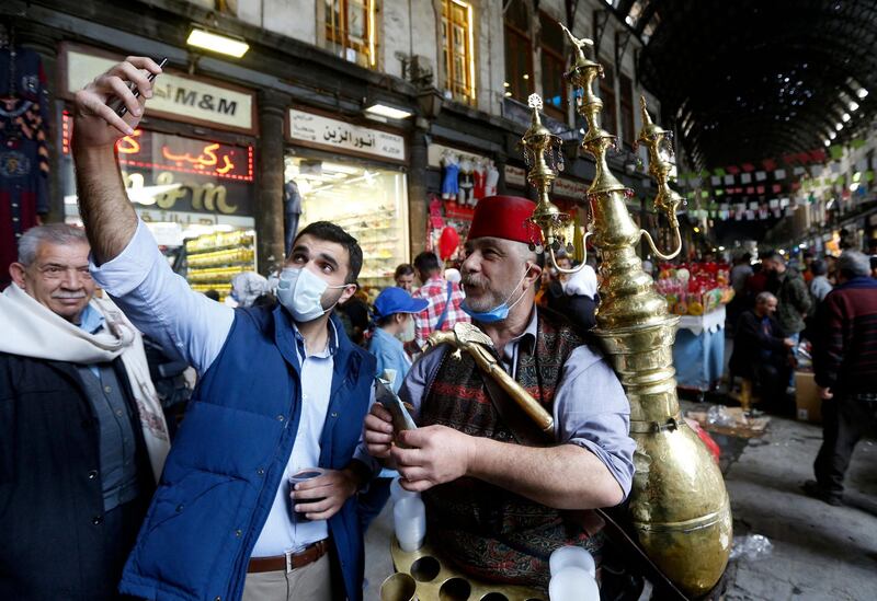 Ishaaq Kremed, a tamarind juice seller, poses for a picture with a customer in Hamidiyah Souq, Damascus. AFP