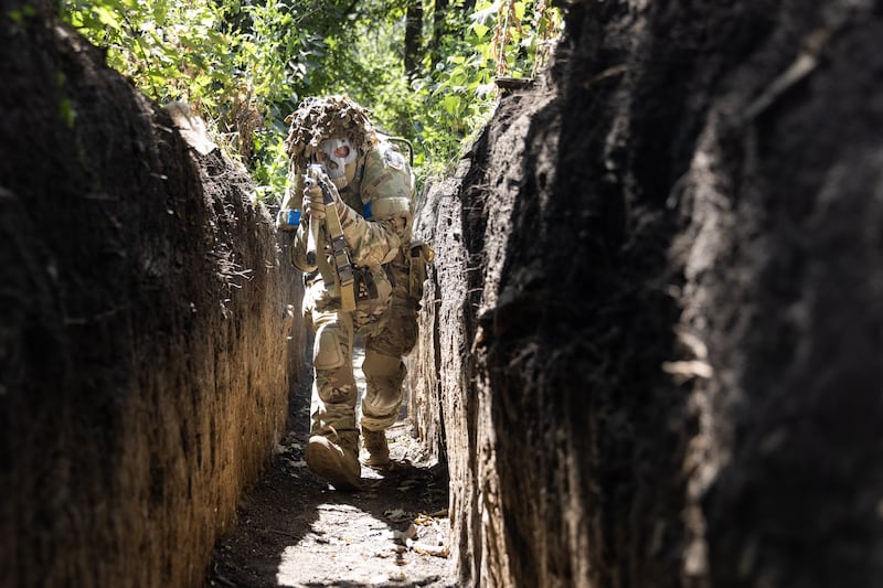 A Ukrainian soldier with the 110th Brigade demonstrates tactical movements in a trench, in Novodarivka, Luhansk region, in July. Getty Images