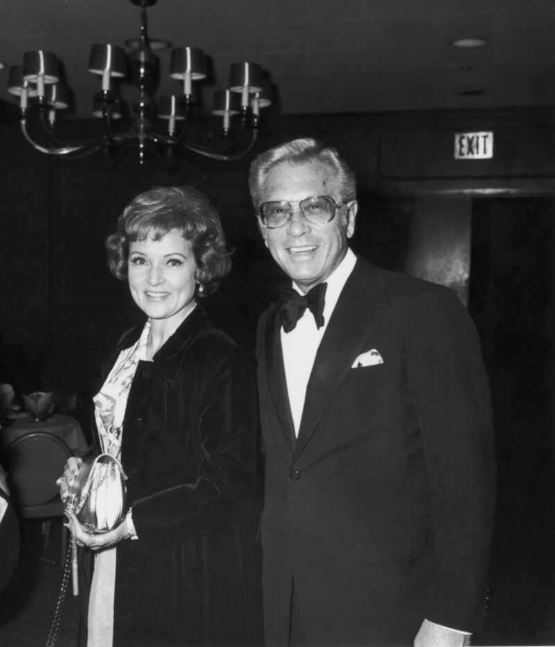 Betty White, in a velvet coat over a dress with a metallic handbag, poses with husband Allen Ludden at an International Broadcasting Awards dinner tribute to Mary Tyler Moore on March 19, 1974. Getty Images