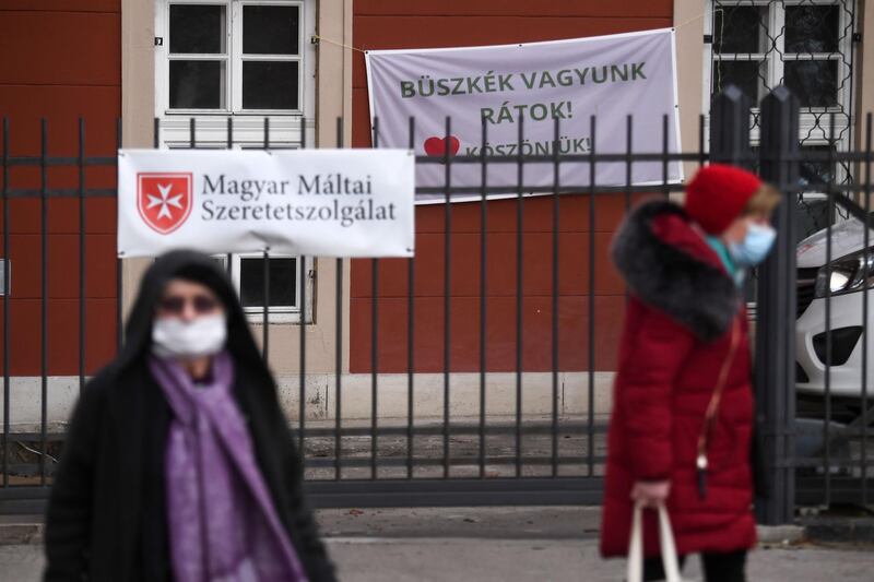 Women wearing face masks walk in front of a hospital with a banner reading 'We are proud of you! Thanks to all of you!', expressing thanks to the medical staff in Budapest, Hungary. AFP