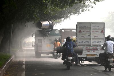 Commuters pass an anti-smog gun spraying water to curb air pollution in New Delhi on Friday. AFP