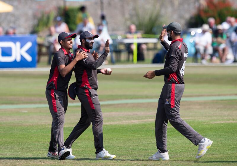 Muhammad Waseem high-fives captain Ahmed Raza after catching Scotland batter Michael Leask. 