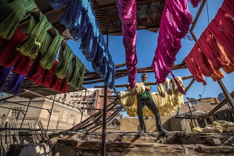 Mohamed Kamal, a 59-year-old dye worker, hangs dyed yarns out to dry in the sun at a traditional hand-dying workshop in the Egyptian capital Cairo's centuries old district of Darb al-Ahmar on January 21, 2020. AFP