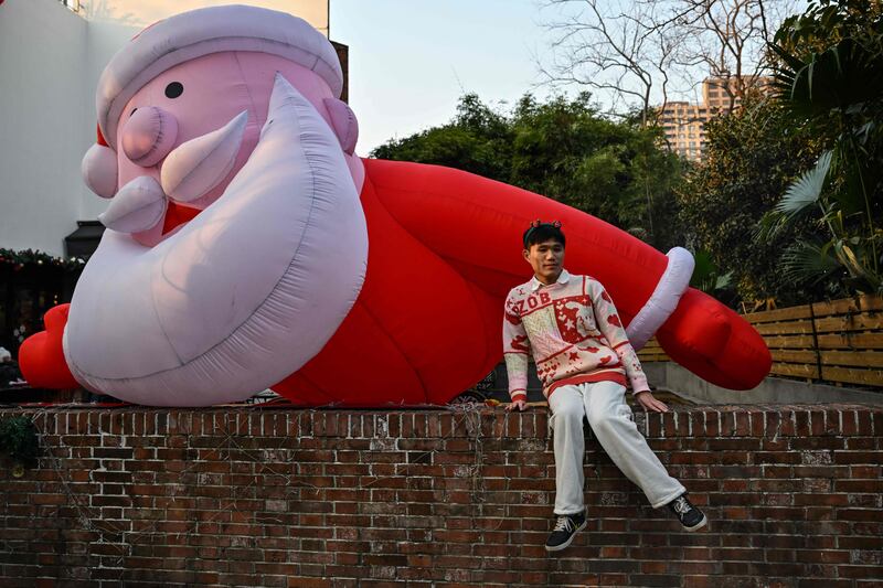 A man poses for pictures next to an inflatable Santa Claus in Shanghai on December 24. AFP