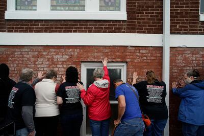 People pray as they hold their hands on a prayer wall outside of the historic Vernon African Methodist Episcopal Church in the Greenwood neighborhood during the centennial of the Tulsa Race Massacre, Monday, May 31, 2021, in Tulsa, Okla. The church was largely destroyed when a white mob descended on the prosperous Black neighborhood in 1921, burning, killing, looting and leveling a 35-square-block area. (AP Photo/John Locher)