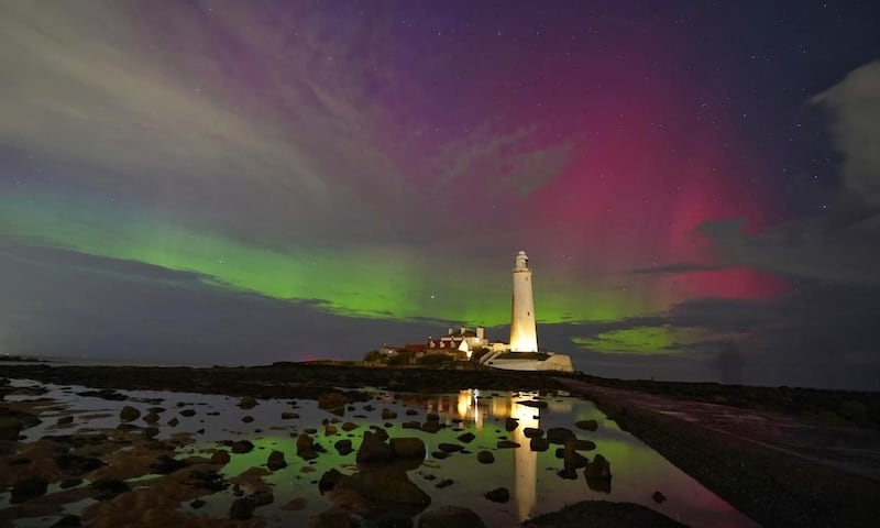 The aurora borealis, also known as the Northern Lights, glows on the horizon at St Mary's Lighthouse in the UK's Whitley Bay. PA