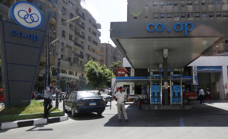 People walk near cars at a Co-Op Petroleum Company petrol station in downtown Cairo, Egypt July 25, 2017. Picture taken through a glass window. REUTERS/Amr Abdallah Dalsh