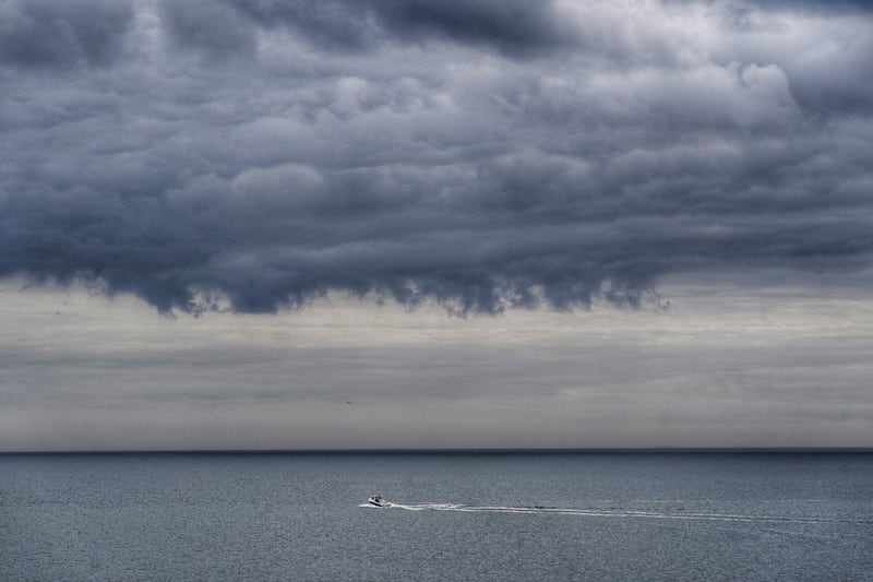 A boat heads out to sea under storm clouds at Tynemouth, on the north-east English coast, in June. PA