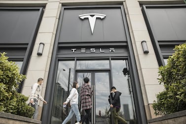 Pedestrians walk past a Tesla dealership in Shanghai, China, the biggest market for electric cars. The company is implementing pay cuts to reduce costs as it shuts some of its operations due to the Covid-19 pandemic. Bloomberg