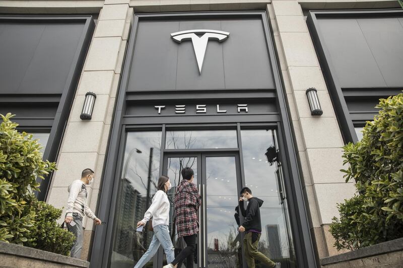 Pedestrians walk past a Tesla Inc. dealership in Shanghai, China on Monday, April 6, 2020. China, the biggest market for electric cars, is considering a reduction in rebates given to buyers and limits on the models that qualify even as it commits to extending the costly subsidy program for another two years. Photographer: Qilai Shen/Bloomberg