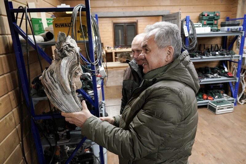 Russian Defence Minister Sergei Shoigu and Russian President Vladimir Putin examine a piece wood for crafting, at Mr Shoigu's workshop, in the Siberian taiga. AP Photo