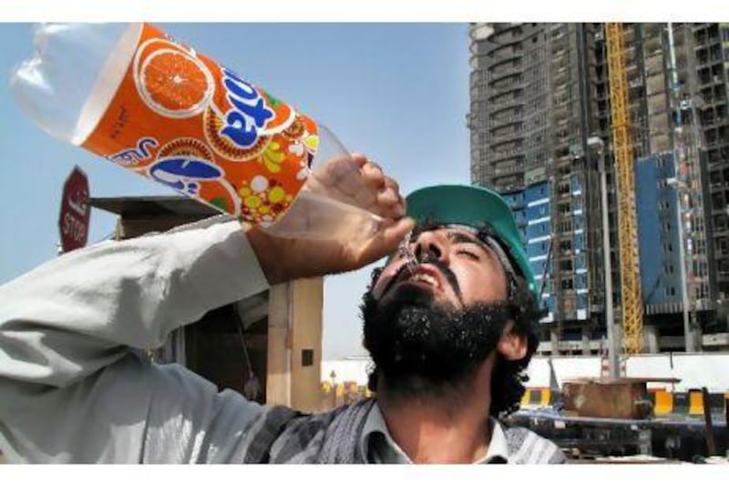 Abu Dhabi, United Arab Emirates - June 17 A construction worker gulps down water while working in the heat. For story on heat. ( Delores Johnson / The National ) *** Local Caption *** dj_17jun09_Heat_001.jpgdj_17jun09_Heat_001.jpg