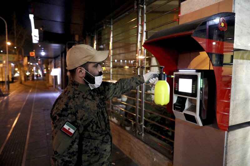 A Revolutionary Guard member disinfects an ATM in Tehran, Iran, March 4. AP
