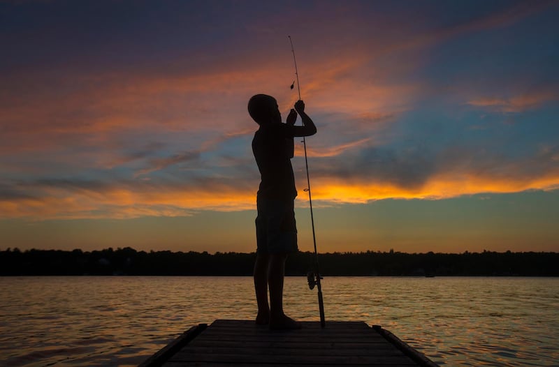 A boy fishes at dusk on Pigeon Lake near Bobcaygeon, Ontario, Canada.  AP