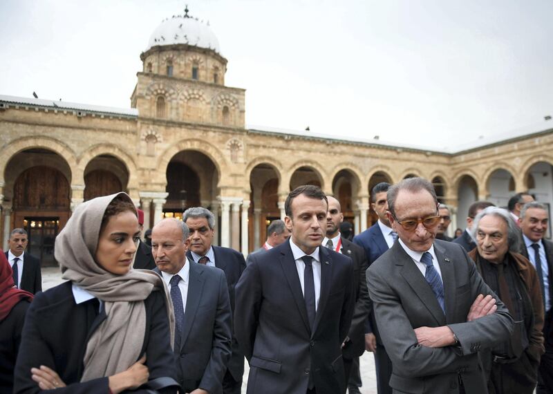 French President Emmanuel Macron (C) stands with Paris' former mayor Bertrand Delanoe (C-R) in the courtyard of the Zitouna mosque in the Medina (old town) of the Tunisian capital Tunis on February 1, 2018, during Macron's first state visit to the North African country. / AFP PHOTO / POOL / Eric FEFERBERG