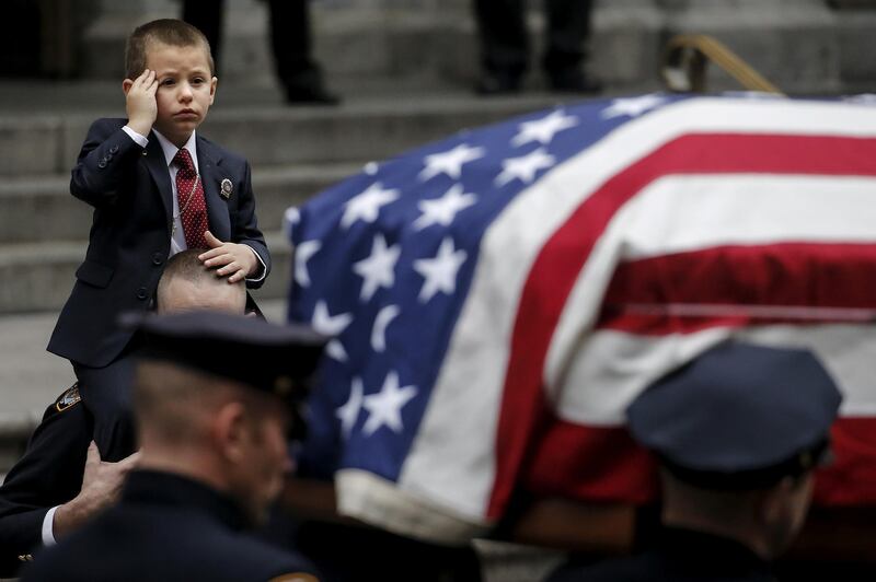 Ryan Lemm salutes the casket of his father, NYPD officer Joseph Lemm, who was killed on duty in Afghanistan. New York, US, December 30, 2015. Reuters