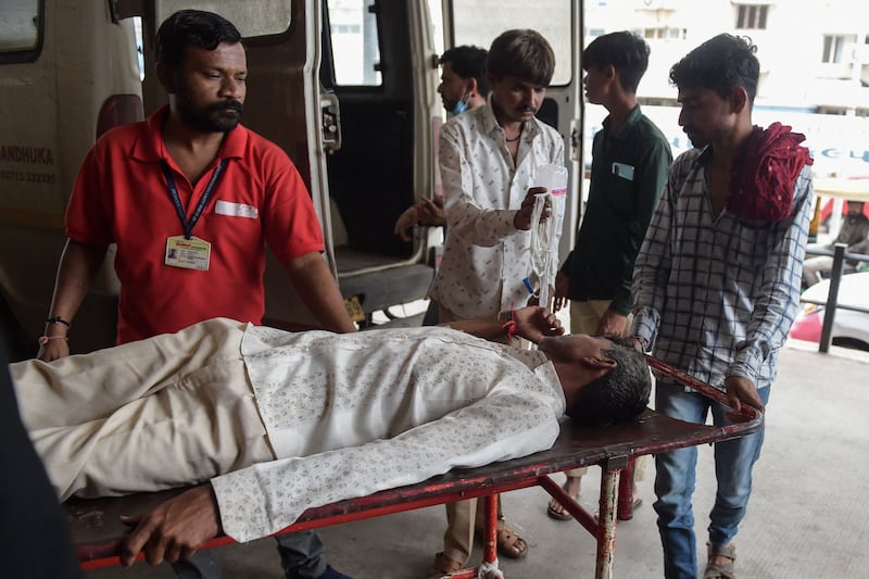 A man is shifted on a stretcher upon arriving in an ambulance at the Civil Hospital in Ahmedabad after suffering health problems due to consuming counterfeit alcohol.  AFP