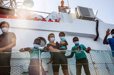 Crew members and migrants stand on the deck of the Louise Michel rescue vessel in the Mediterranean sea. AP Photo/Santi Palacios