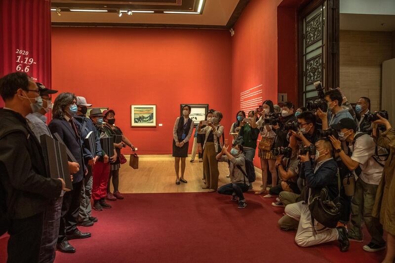 Photographers wearing protective face masks take photos of guests during 'A tribute to donors' exhibition at the National Art Museum of China on the first day after reopening. EPA