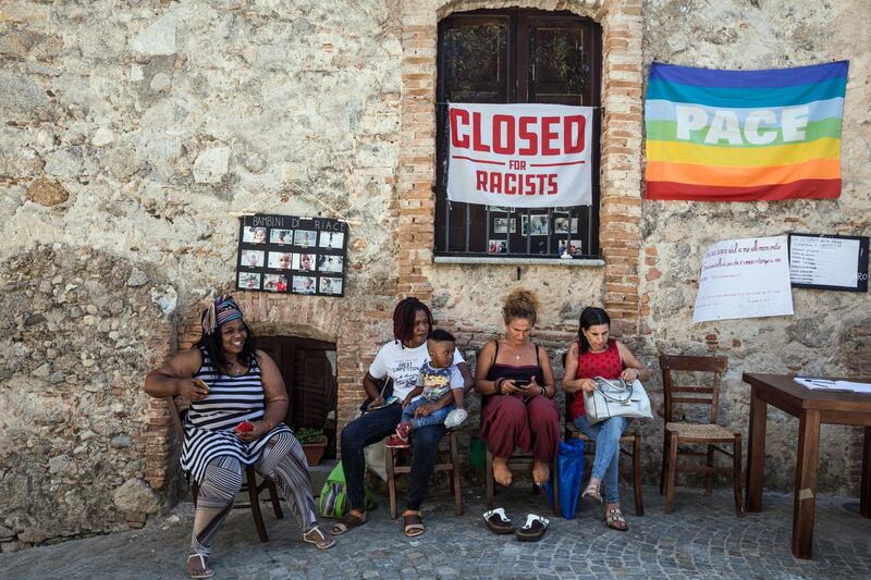 Some migrants and locals gather for a talk in front of the "Taverna Donna Rosa", the main centre for the protest against the central government. The National/Giacomo Sini