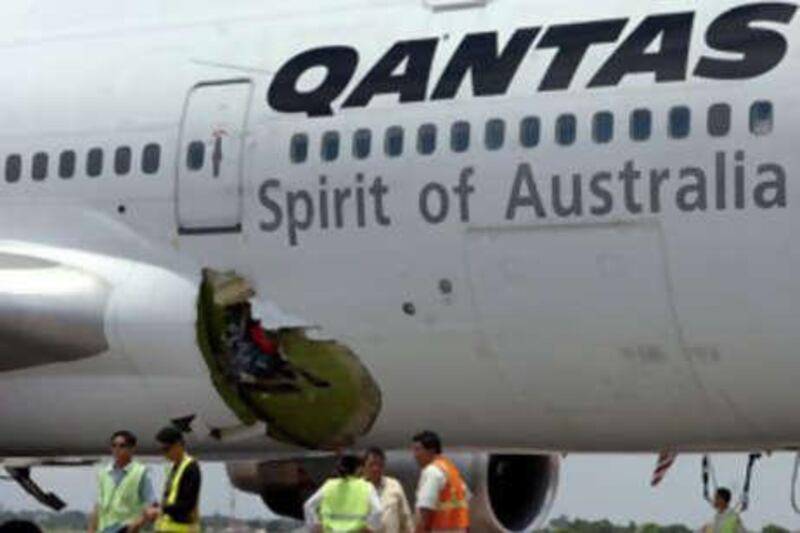 Workers and security personnel stand next to the hole of the Melbourne-bound Qantas Boeing 747 after it made an emergency landing in Manila.