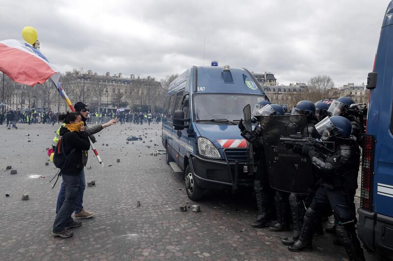 Yellow-vest protesters holding a French national flag argue with riot police on the Place de l'Etoile in Paris on March 16, 2019. AFP