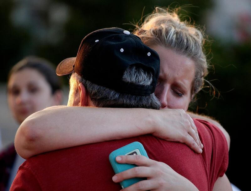 Rachel Riutzel hugs Russ McKay as he looks at a makeshift memorial for his friends before a candlelight vigil in the parking lot of Ride the Ducks Friday, July 20, 2018 in Branson, Mo. One of the company's duck boats capsized Thursday night resulting in over a dozen deaths on Table Rock Lake. (AP Photo/Charlie Riedel)
