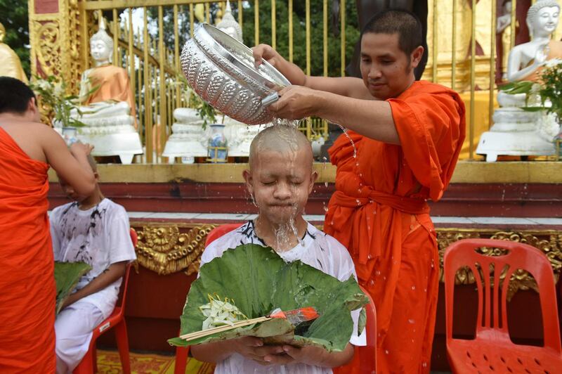 A monk bathes the shaved head of the rescued boy. AFP