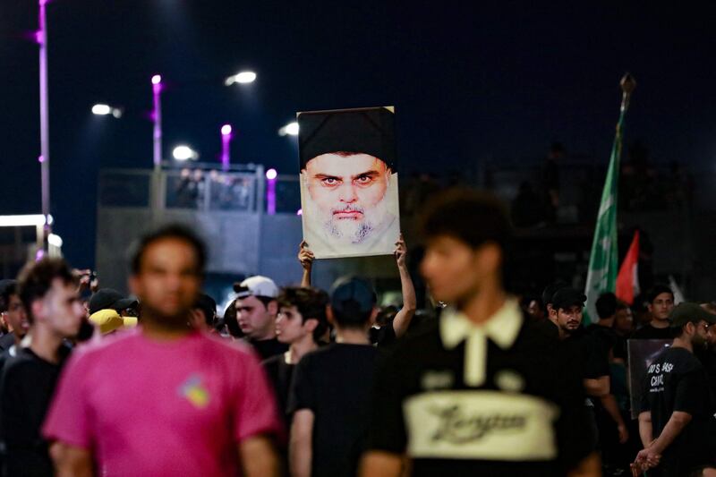 Supporters of Mr Al Sadr carry his portrait as they protest near Baghdad's Green Zone. AFP