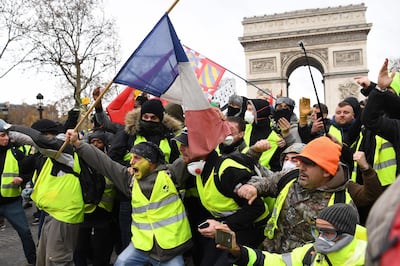 TOPSHOT - Protestors wearing "yellow vest" (gilet jaune) gesture on December 8, 2018 near the Arc de Triomphe in Paris during a protest against rising costs of living they blame on high taxes. Paris was on high alert on December 8 with major security measures in place ahead of fresh "yellow vest" protests which authorities fear could turn violent for a second weekend in a row. / AFP / Eric FEFERBERG
