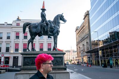Gallery steward Louisa Mcgeachie stands by Glasgow's Duke of Wellington statue, which sports a traffic cone and is considered to be the first original piece of 'street art'. PA 