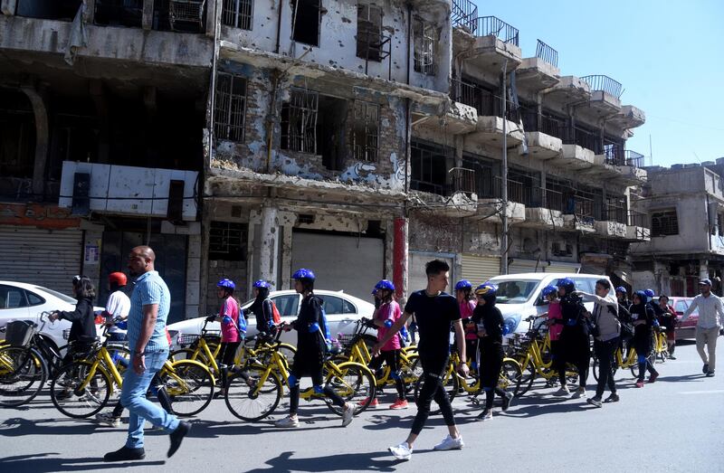 Female cyclists walk towards the starting line, past a building destroyed in fighting with ISIS during its occupation of Mosul between 2014 and 2017. The race was also intended to draw attention to the need for more reconstruction efforts. EPA