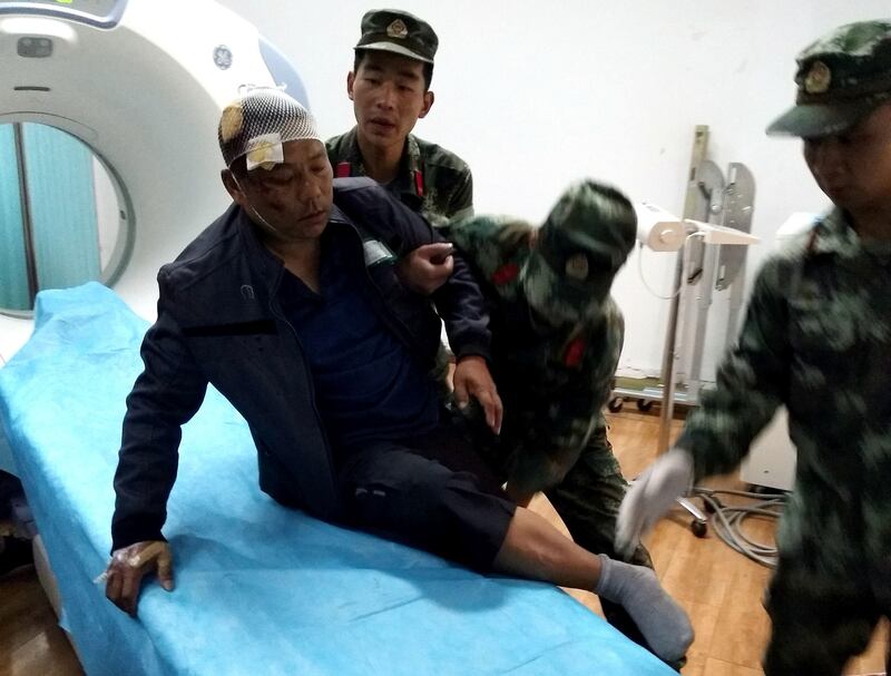 Paramilitary police help an injured man at Jiuzhaigou County Hospital in Jiuzhaigou, in southwest China's Sichuan province on August 9, 2017, the morning after an earthquake struck the area. 
At least 12 people were killed when a 6.5-magnitude earthquake struck southwestern China, government sources said on August 9, but the toll was expected to climb as news trickles out of the remote mountainous region. / AFP PHOTO / STR / China OUT