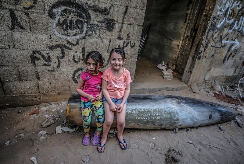 Palestinian sisters sit on an unexploded missile fired in an Israeli air strike on Gaza city. EPA