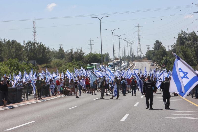 Israeli demonstrators wave flags as they block Highway 443 between Jerusalem and Tel Aviv, near Modiin. AFP