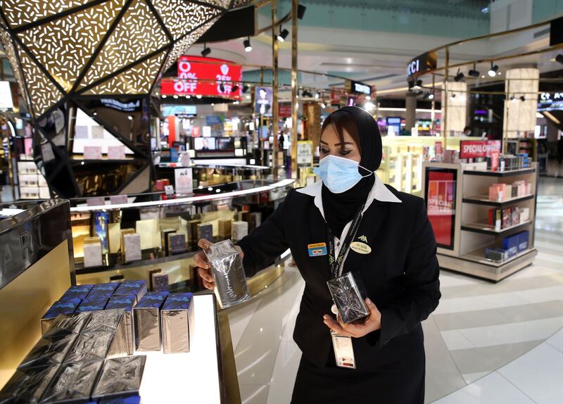 A duty-free employee, wearing a protective face mask due to the Covid-19 pandemic, restocks a shelf at the Muscat international airport in the Omani capital on October 1, 2020.  / AFP / MOHAMMED MAHJOUB
